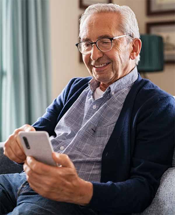 Gl&uuml;cklicher &auml;lterer Mann, der zu Hause telefoniert